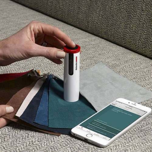 A colorimeter measuring fabric swatches beside a phone