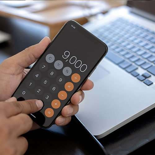 A phone calculator showing a quote next to a laptop